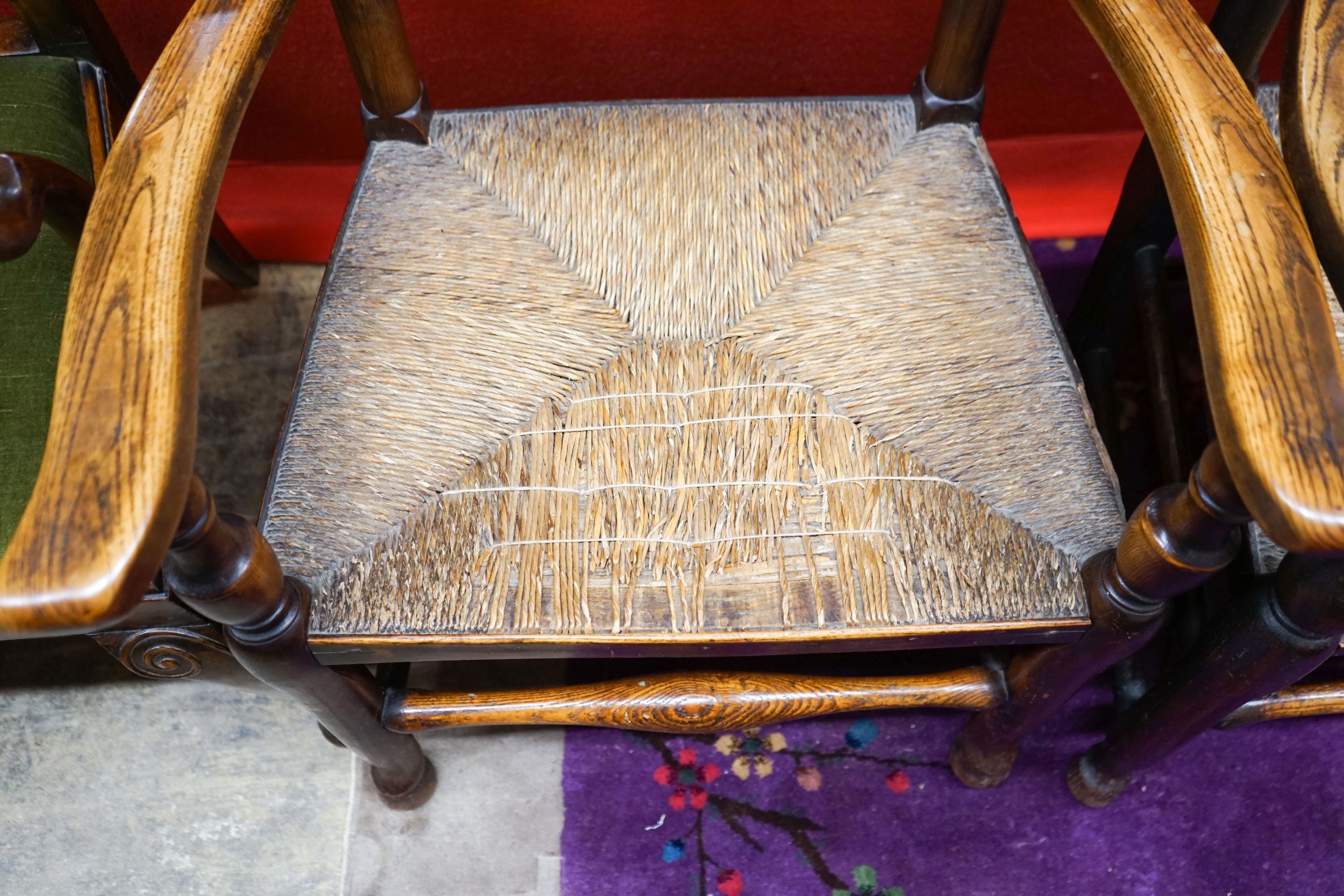 A near pair of Lancashire ash and elm rush seat spindle back elbow chairs